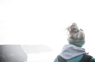 woman in blue shirt sitting on rock